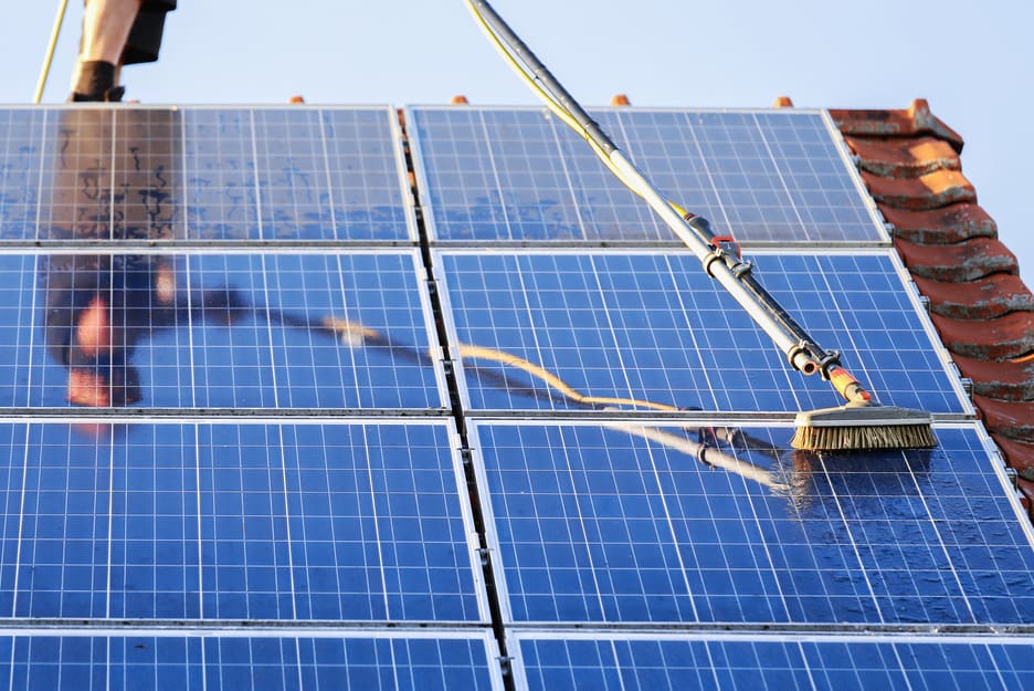 Cleaning solar panels with brush and water